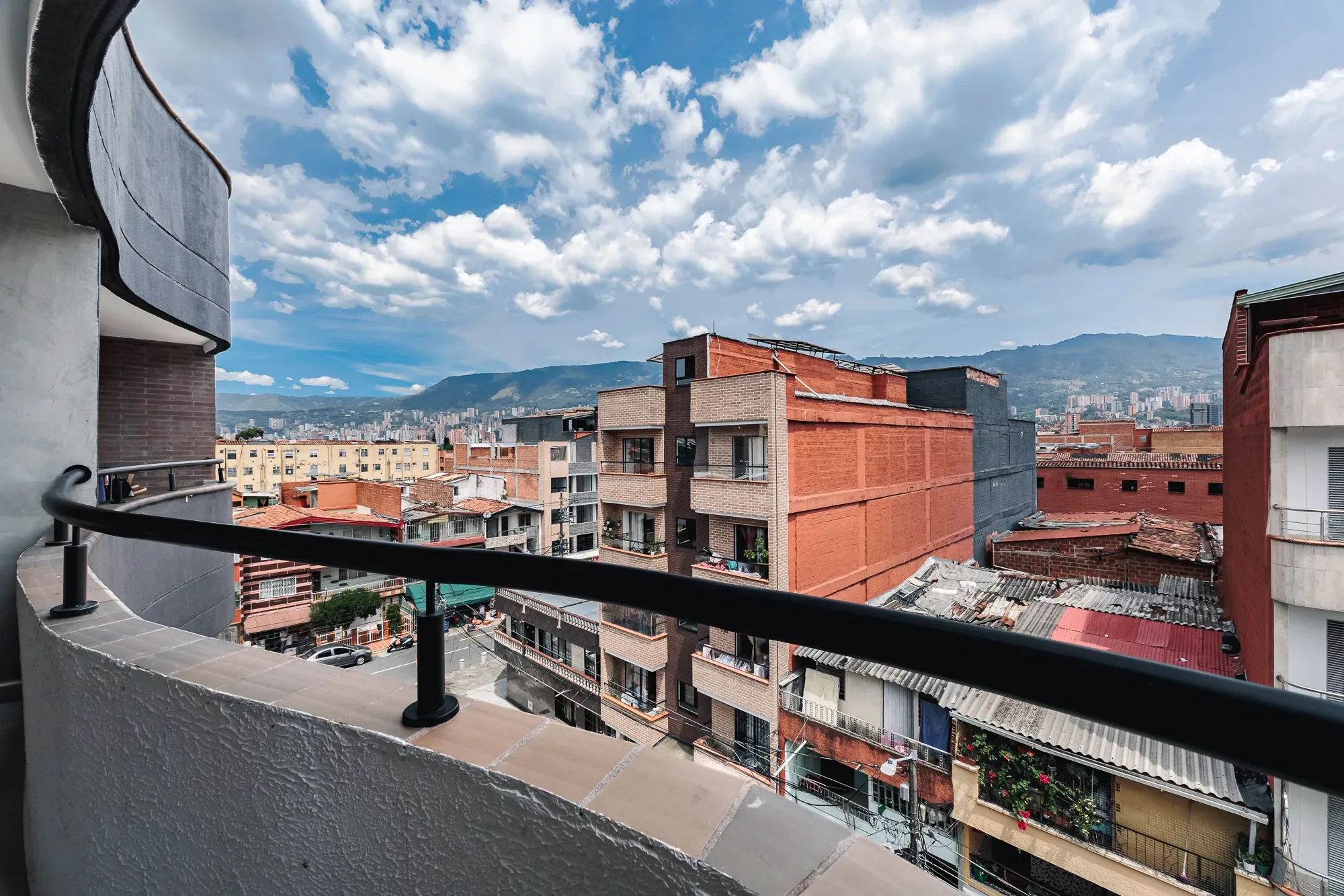 The rooftops of Itagüí and the mountains of the Aburrá Valley under a summer sky