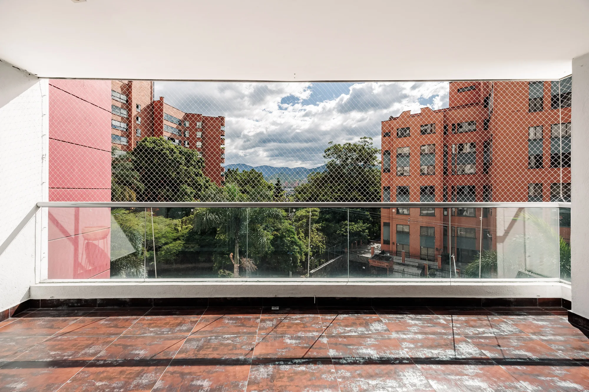 Large terracotta-tiled balcony looking over the greenery and brick towers of south El Poblado at Balcón Verde