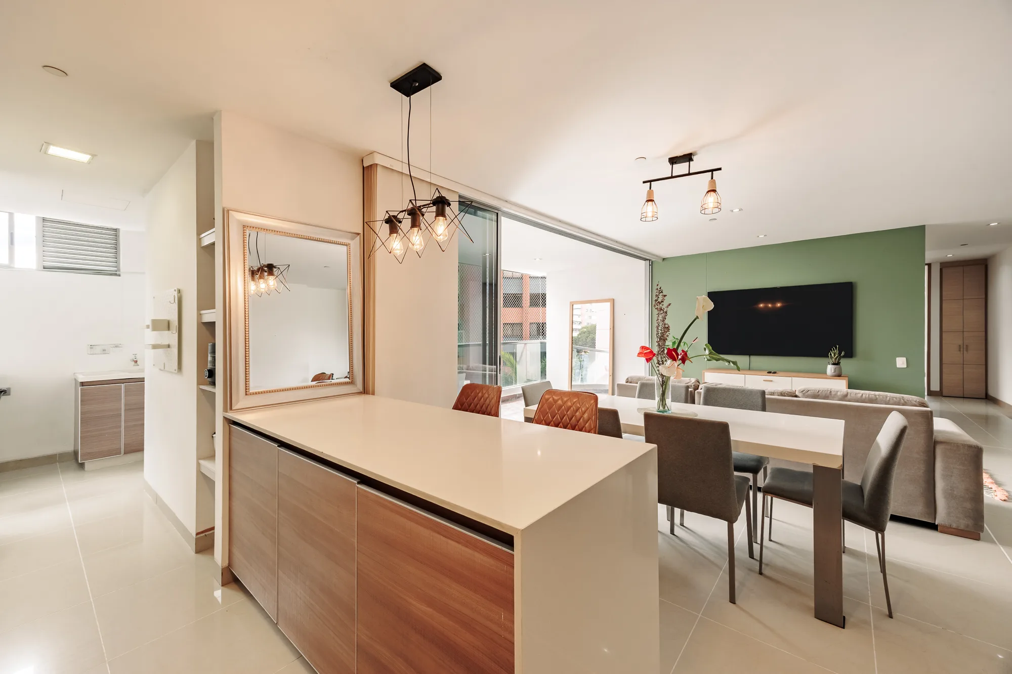 Kitchen island in light wood seen from the hallway, dining beyond, at Balcón Verde, El Poblado