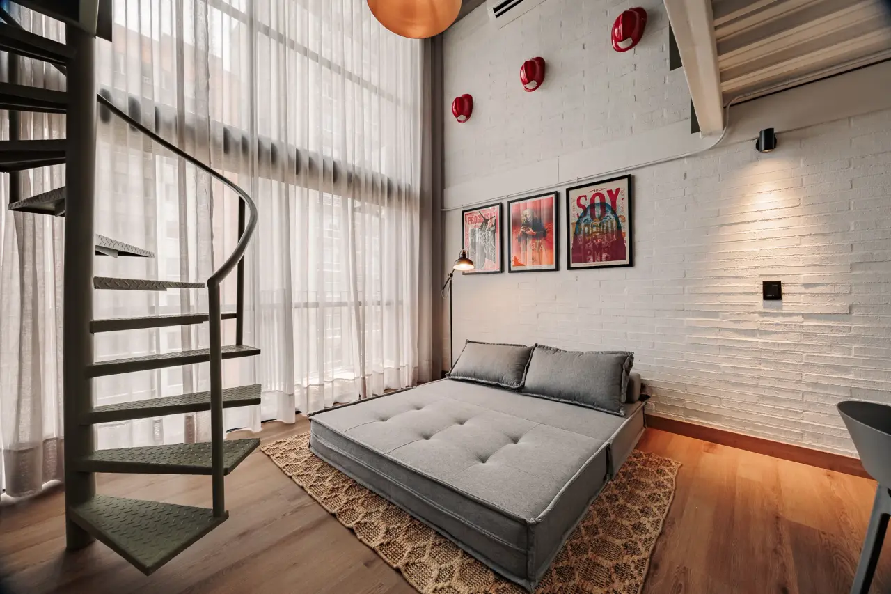 Sofa and spiral stair under the framed prints at Downtown Loft
