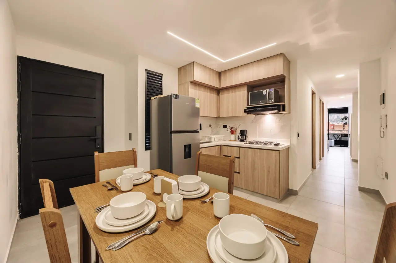 Dining table for four, with the kitchen and the hallway behind it