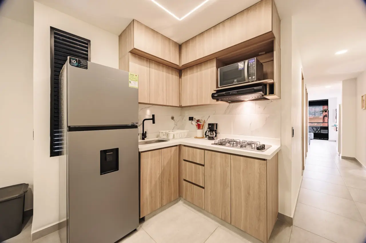 Kitchen with warm wood cabinets, a microwave, a gas stove and a fridge with a water dispenser