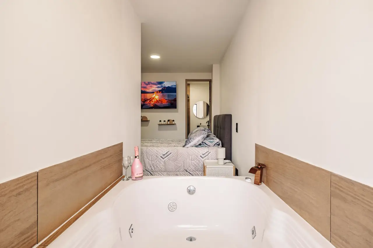 The jacuzzi in the foreground and the main bedroom beyond it