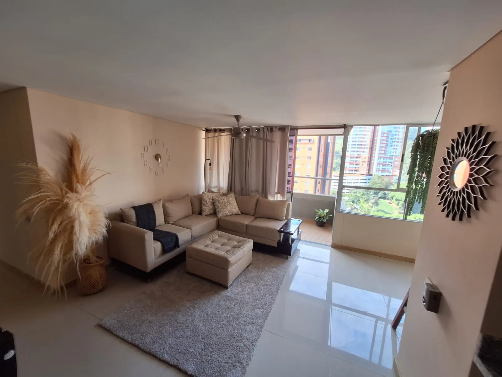 Sabaneta Parkside — bright living room with a sectional sofa opening to a city and mountain view, Sabaneta, Medellín