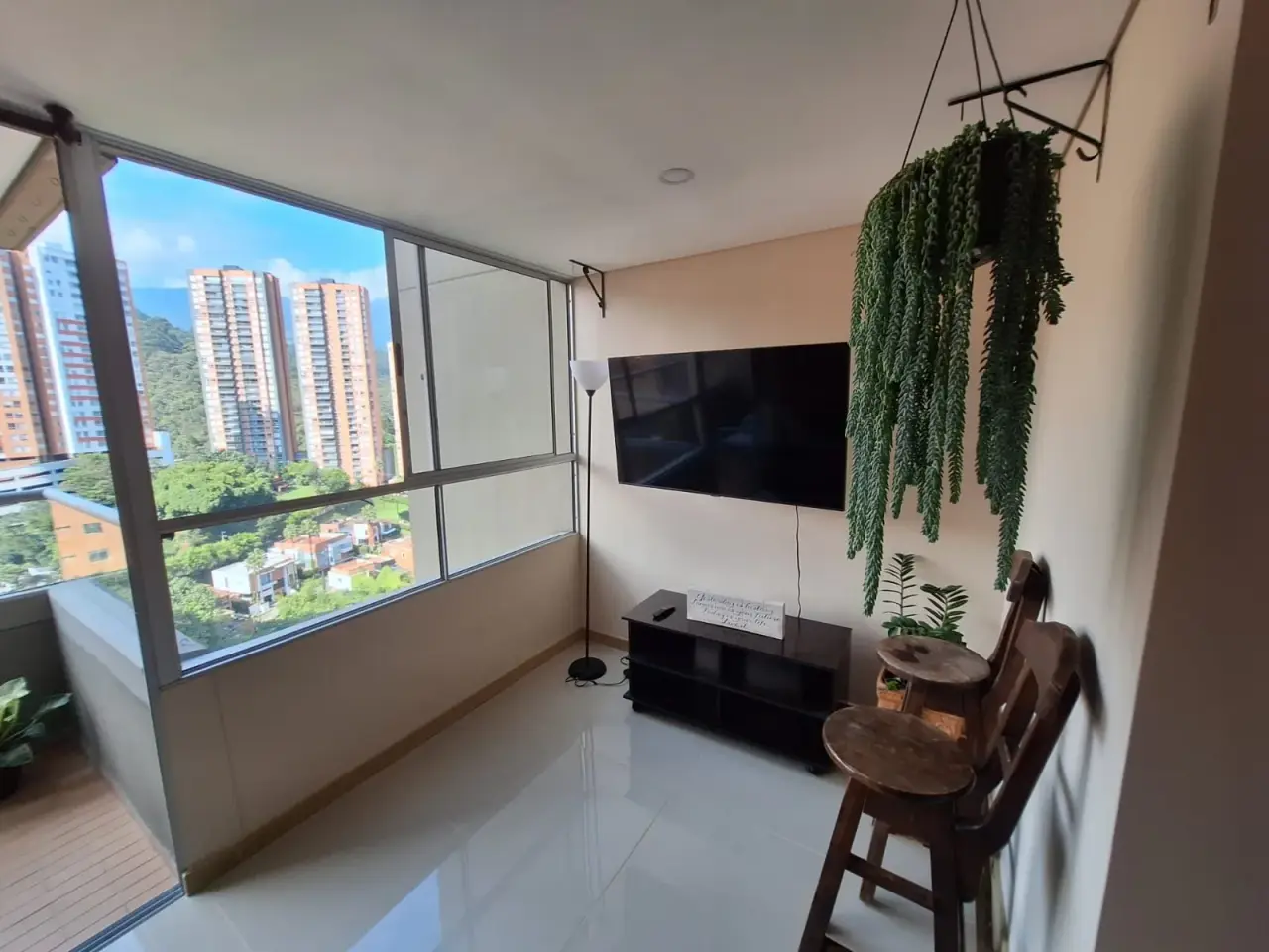 TV corner with a wall-mounted screen and a window onto the towers at Sabaneta Parkside