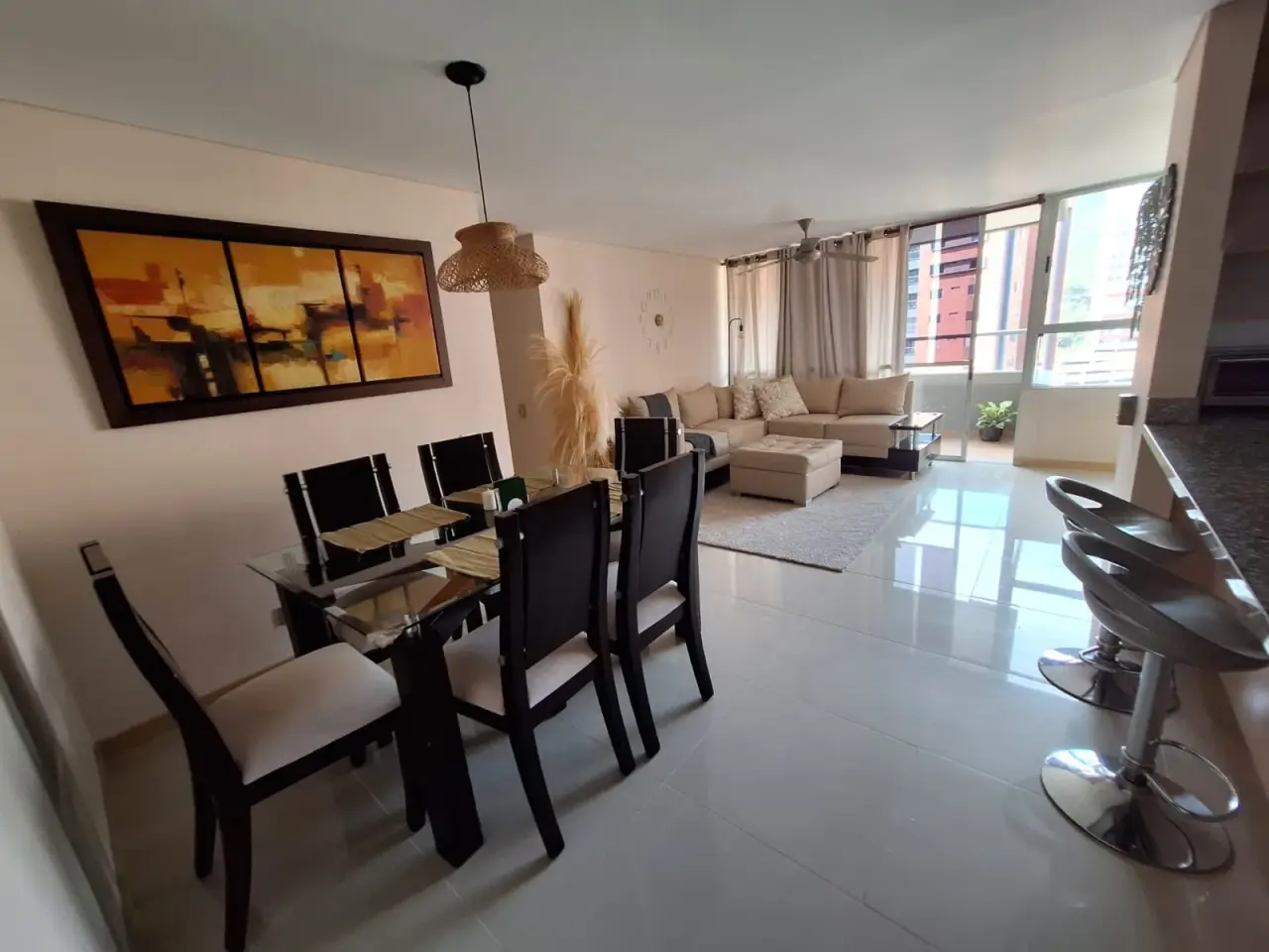 Dining table beside the breakfast bar, with the living room behind, at Sabaneta Parkside