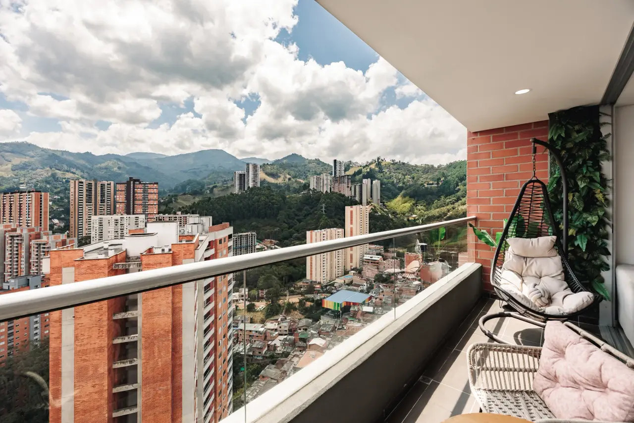 The balcony's hanging chair against the brick towers and the mountains of the Aburrá Valley